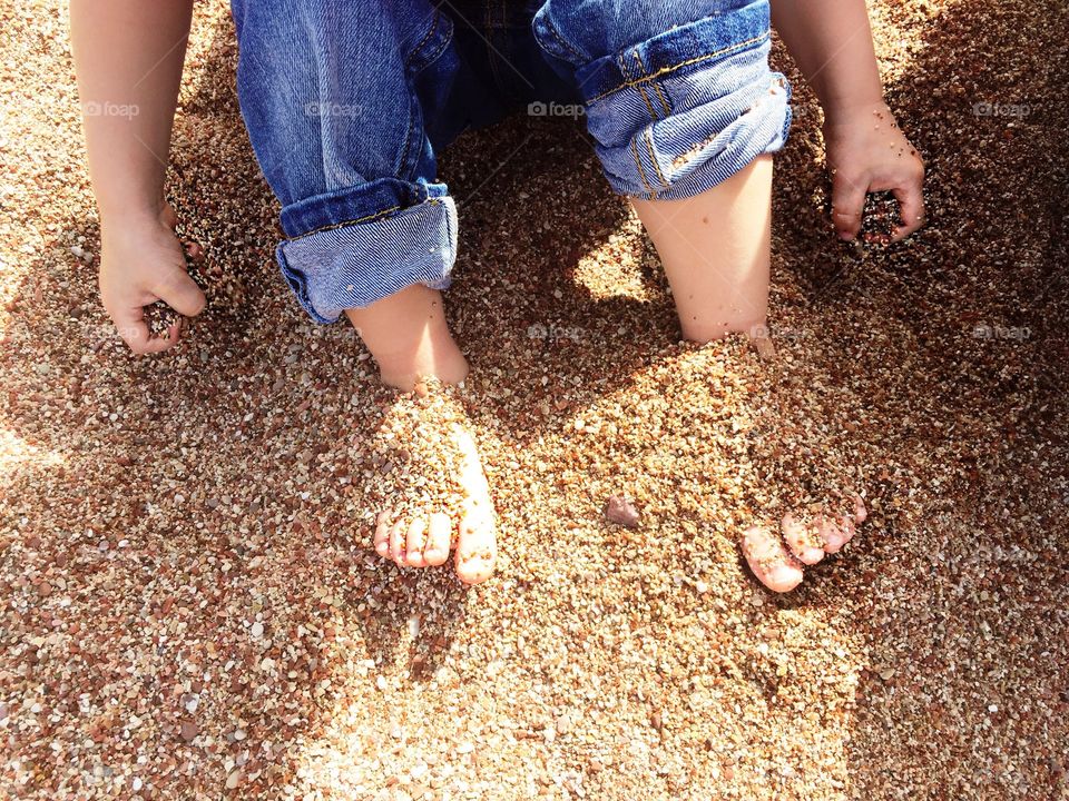 High angle view of child feet in the sand