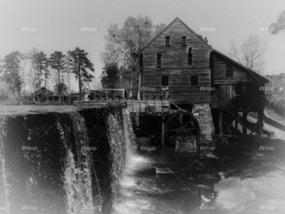 Antique or vintage filter on the waterfall and the old gristmill with the flume and waterwheel in view at Historic Yates Mill County Park in Raleigh North Carolina, Triangle area, Wake County. 