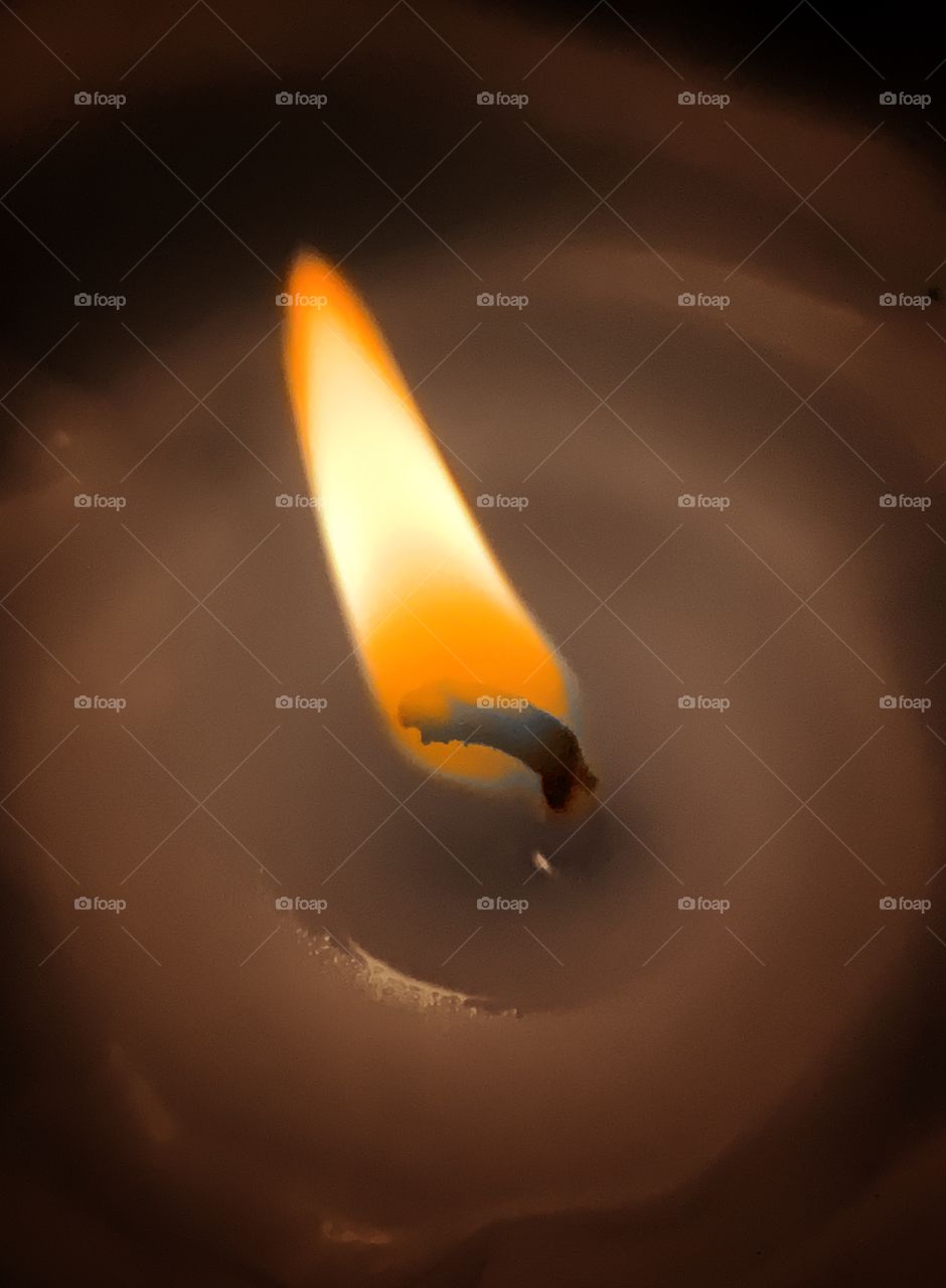 highlight of a flame in a candle surrounded by wax