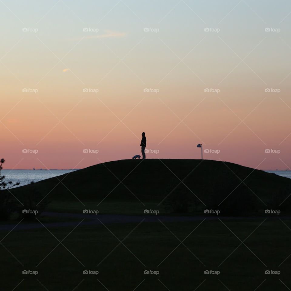 One man stand. One man standing on a hill in the sunset