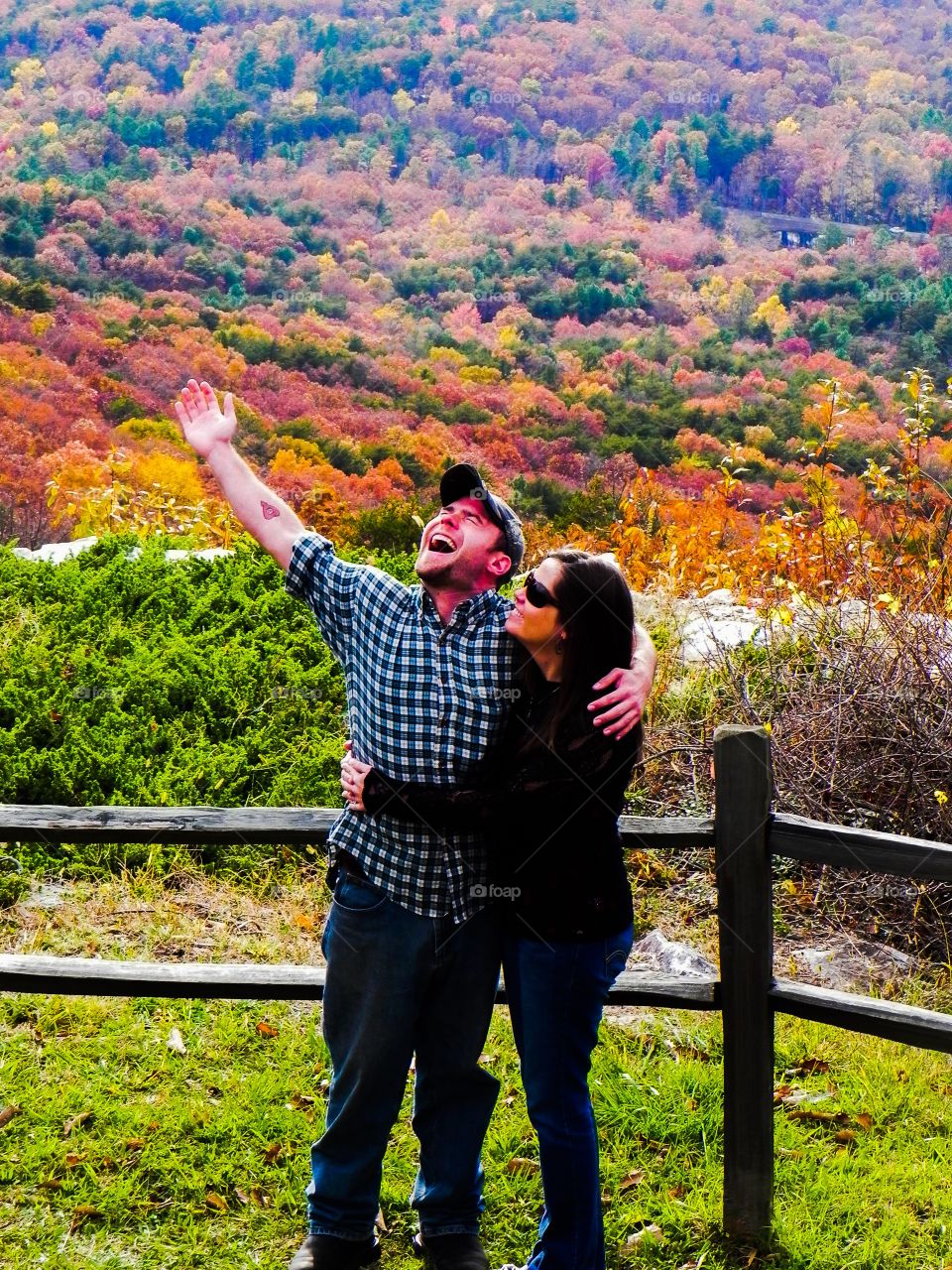Happy young couple standing near railing during autumn