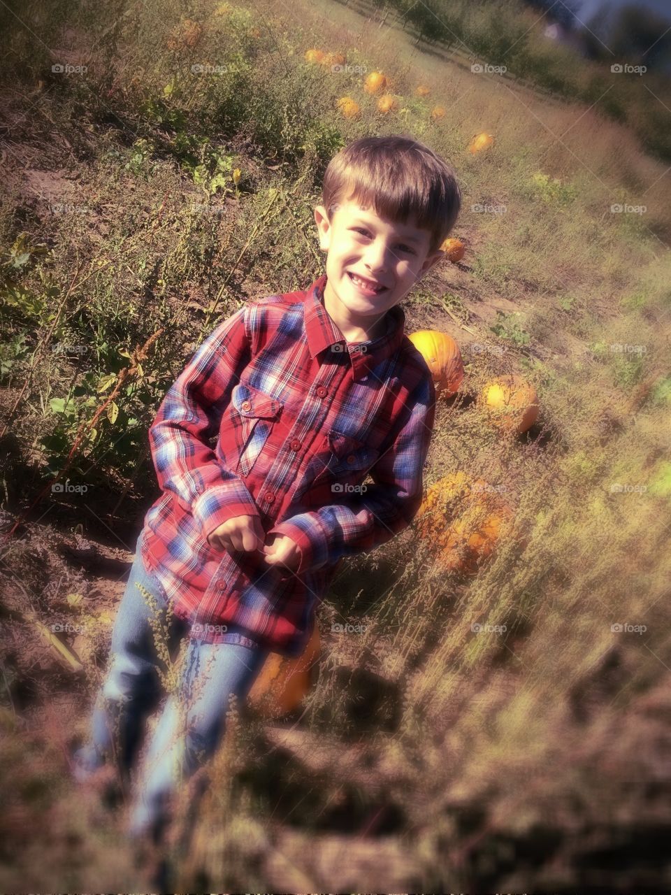 Small boy standing near pumpkin