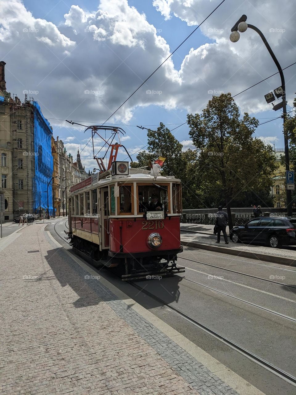 An ancient streetcar on the streets of modern Prague.