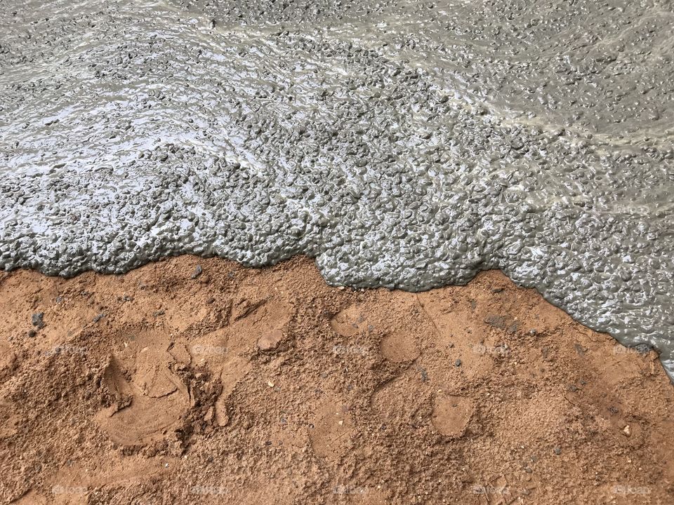 Fresh concrete slowly flow on ground in construction work