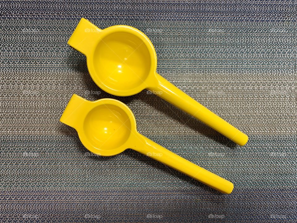 Lemon squeezer with sky blue place mat. Round, yellow, kitchenware. Hand juicer. 