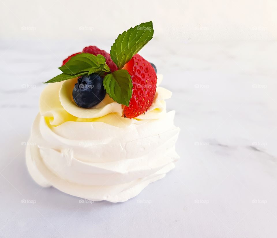 Dessert Pavlova made by meringue, cream and fresh fruits - lights and delicious, perfect for summer day.