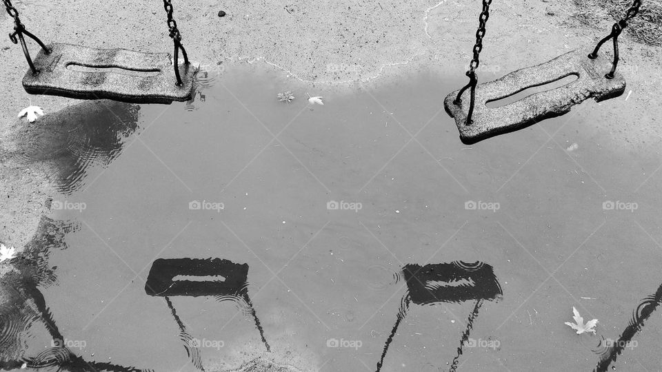 Reflection of old children's swing in a rain puddle