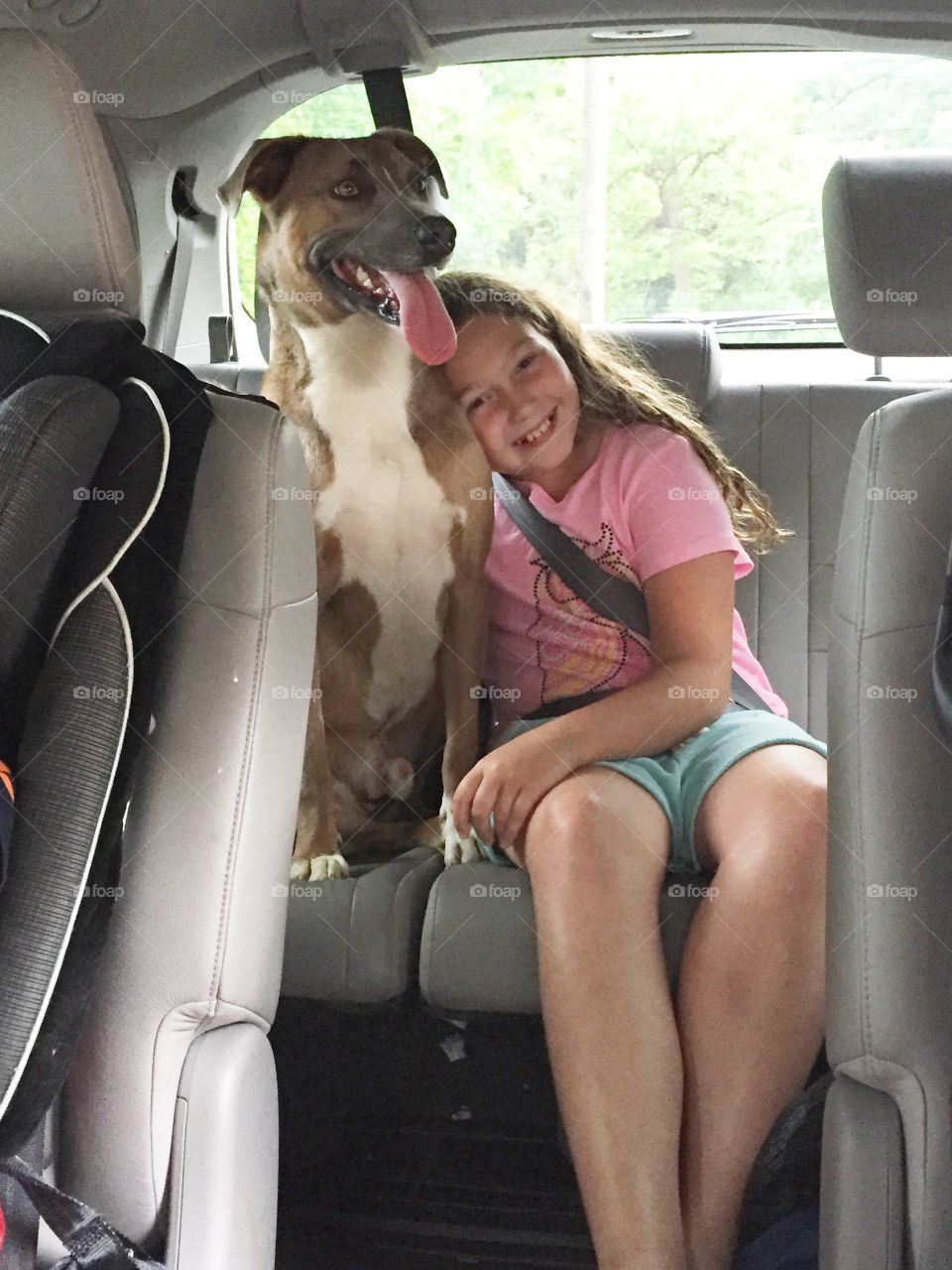 Girl with dog sitting in car