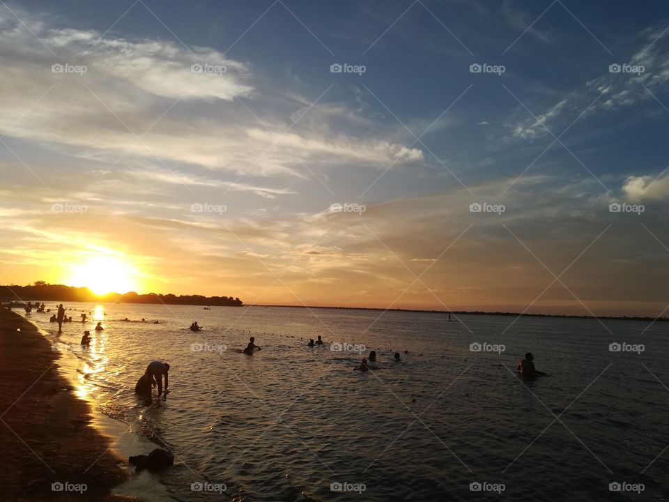 People bathing in the river, with a beatiful sunset