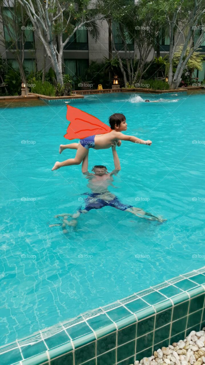 Kid doing superman. father holding his son do act as superman