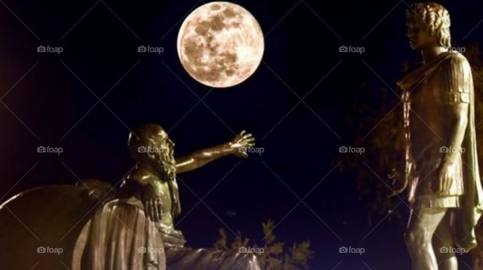 la luna acompañando a dos estatuas en la noche oscura