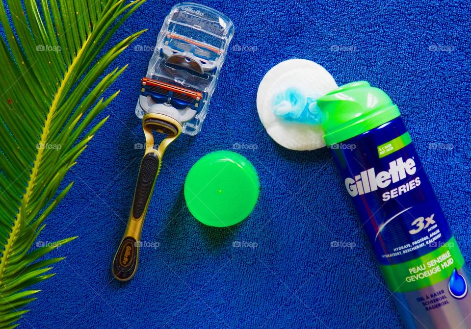 Gillette shaving cream and razor on a blue towel.