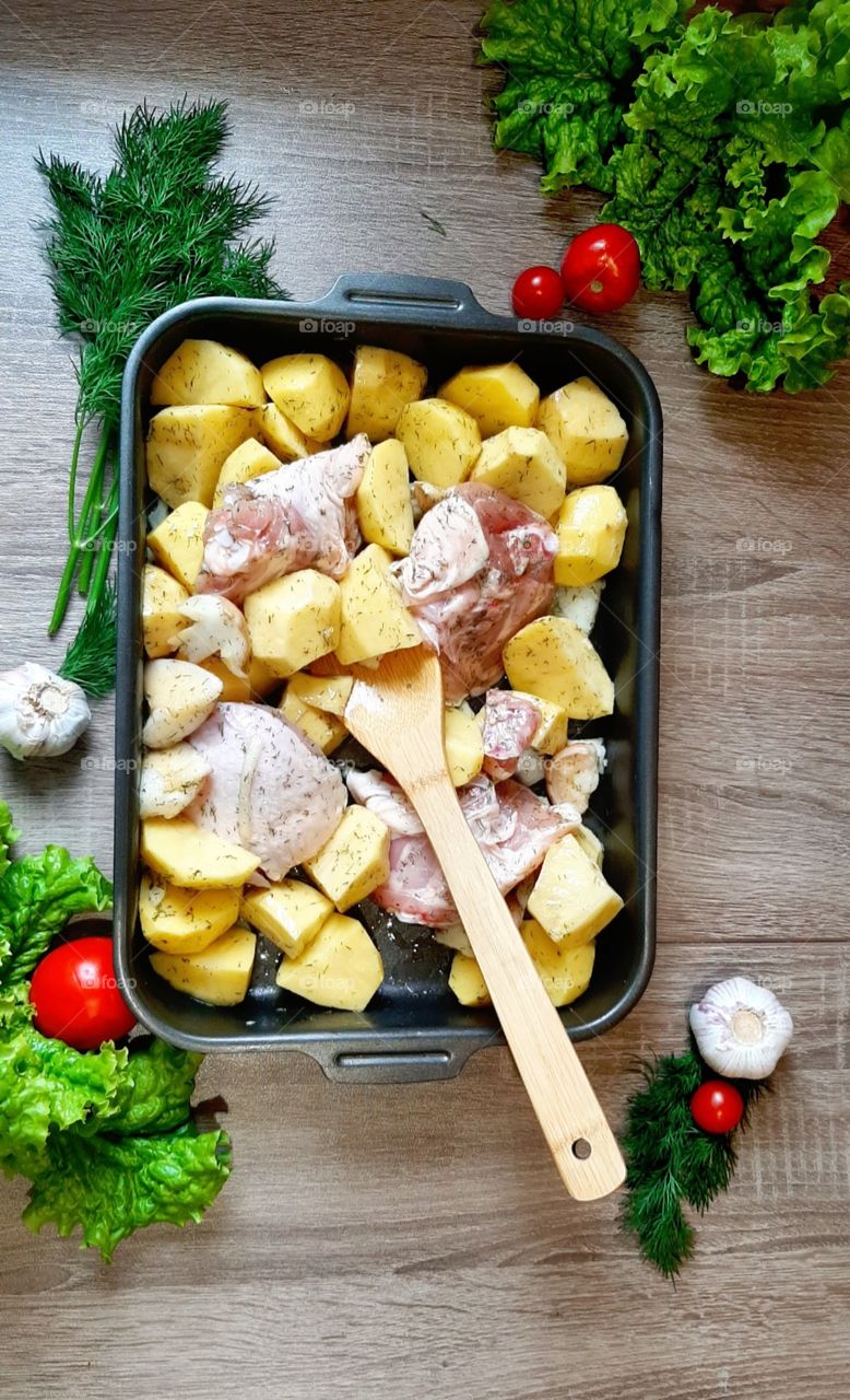 Chicken with potatoes in garlic and dill before baking.