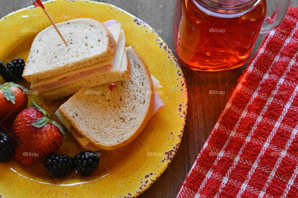 Ham and cheese sandwich with fruit and a glass of juice