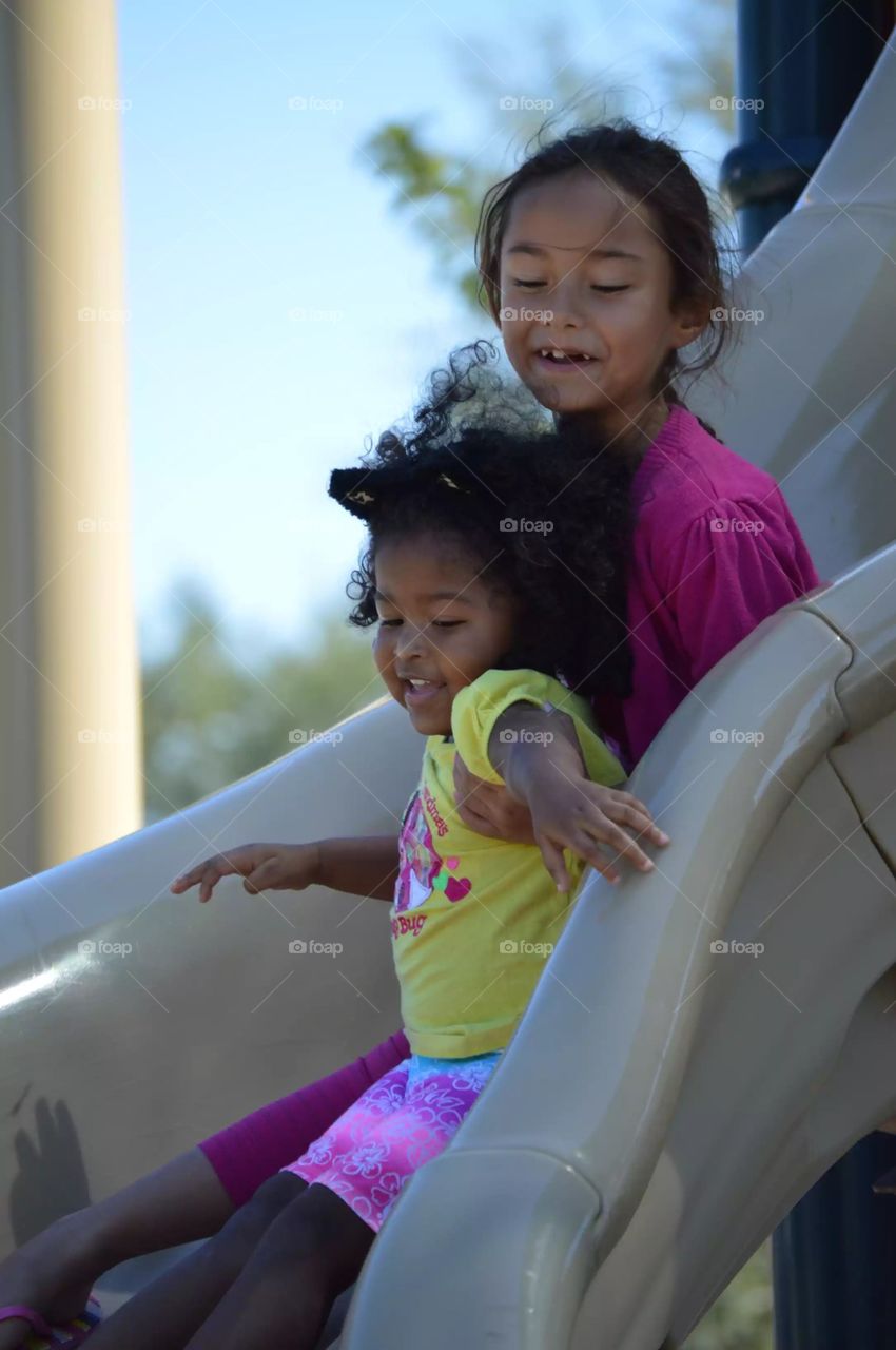 Asian girls enjoying on slide in park