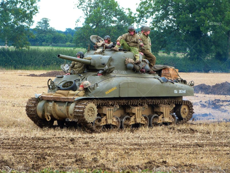Soldiers riding in to battle on a tank, World War Two reenactment
