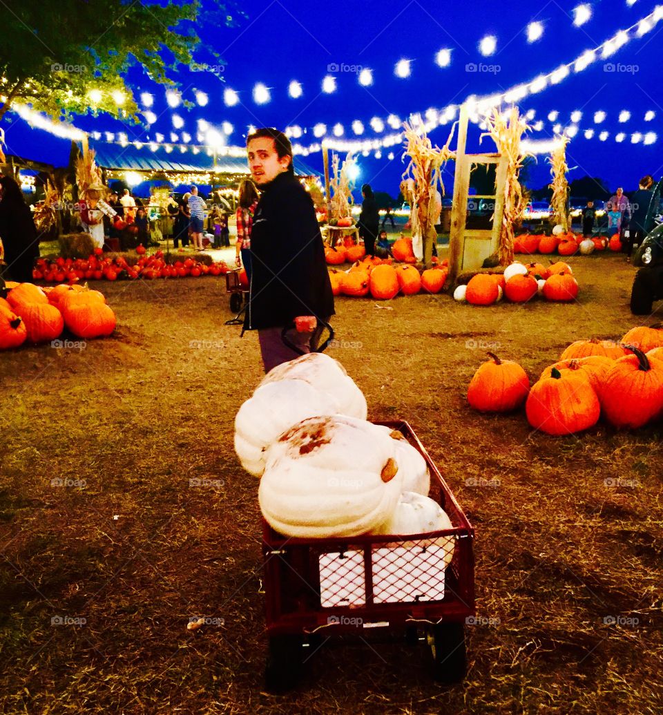 Man carrying cart of fresh pumpkin at night