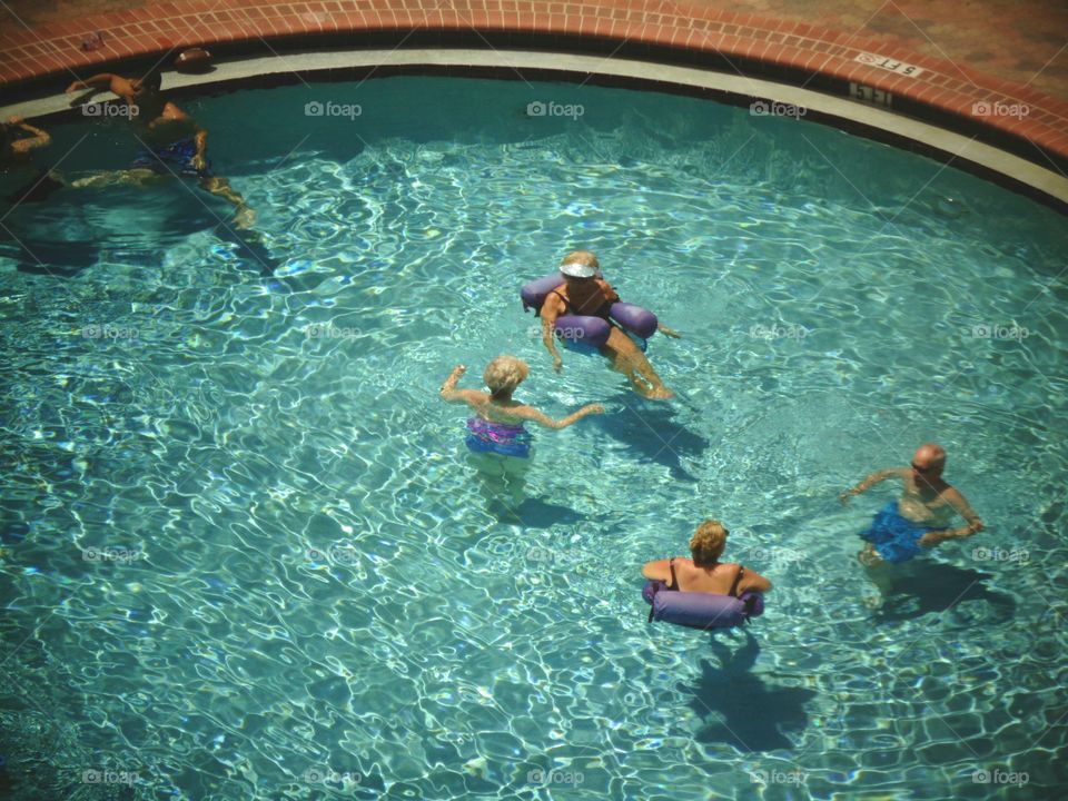 Swimming pool, pic from above. Round pool, older people floating, laughing.