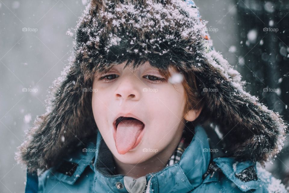 Little boy catching a snowflake on his tongue