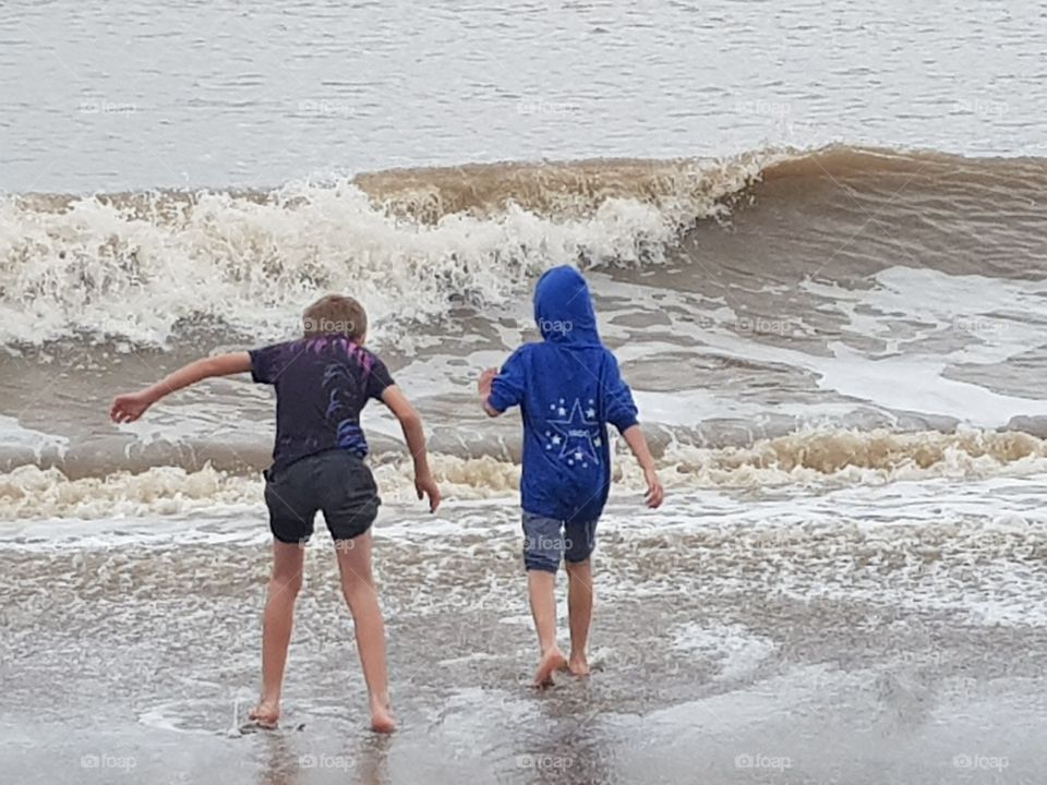 Two children playing at the seaside in the waves
