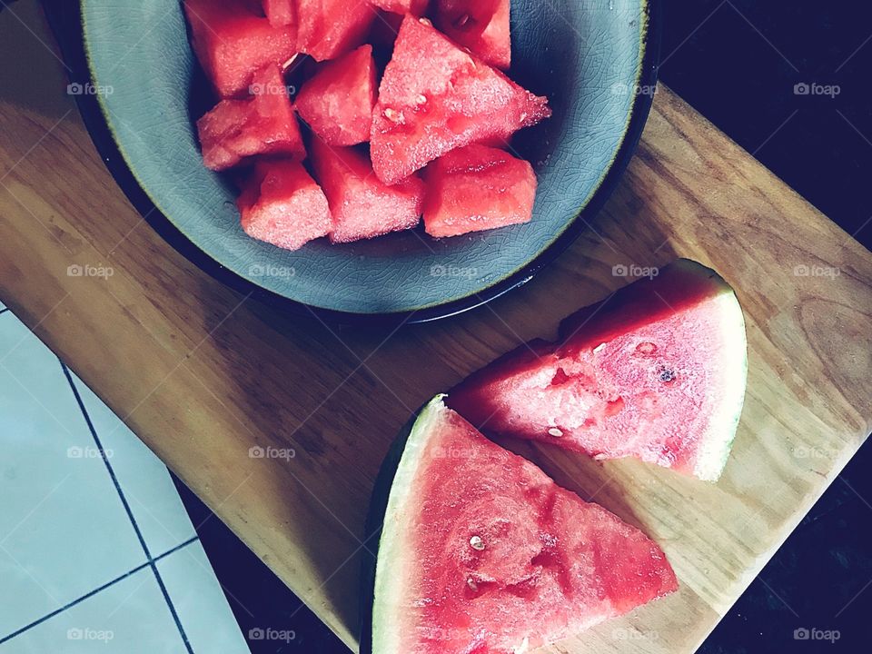 Delicious watermelon sliced up in a bowl and cutting board 