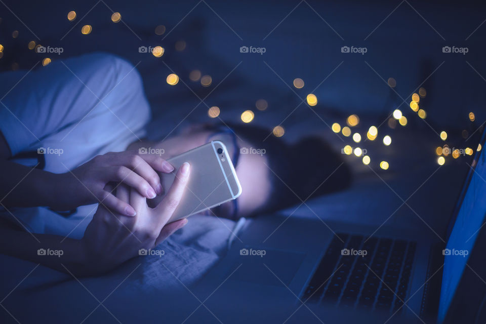 A lady laying on bed and using her mobile 
