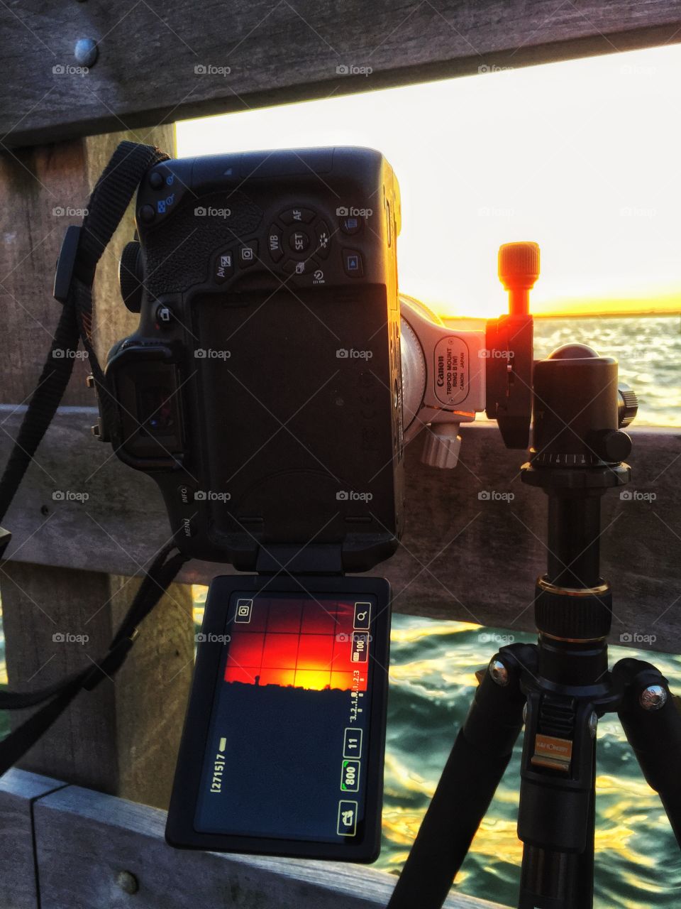 View of the LCD screen of a DSLR camera capturing a vibrant sunset on a fishing pier. 