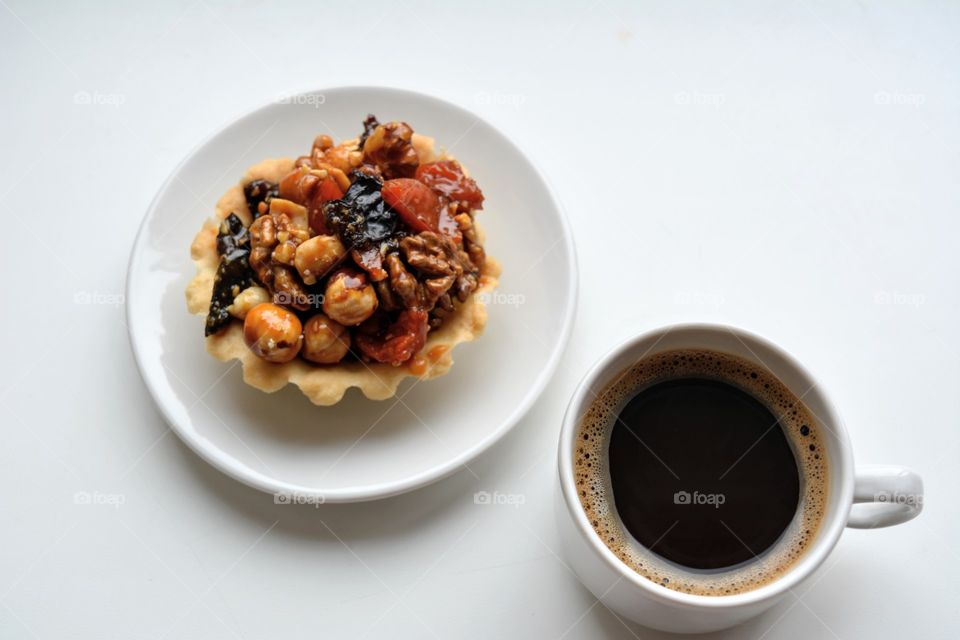 cup of coffee and cake with nuts on a white top view background