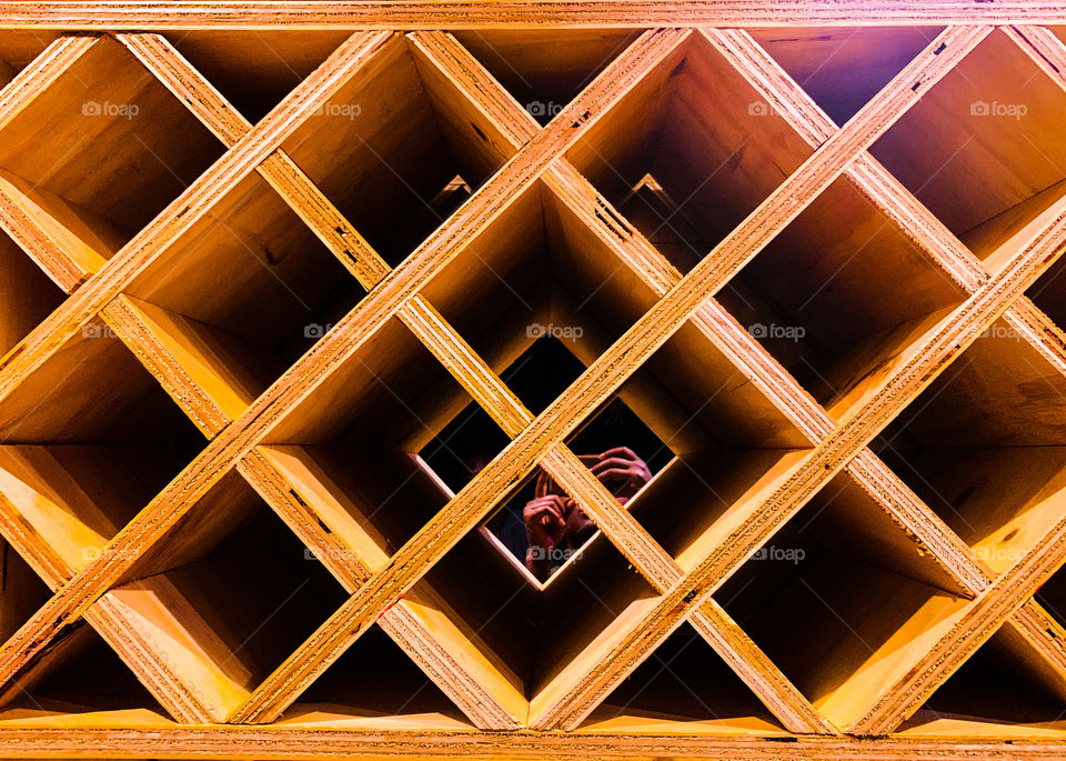 A patterned wooden wine rack made of cubicles with a mirror background. Modern architectural designs.