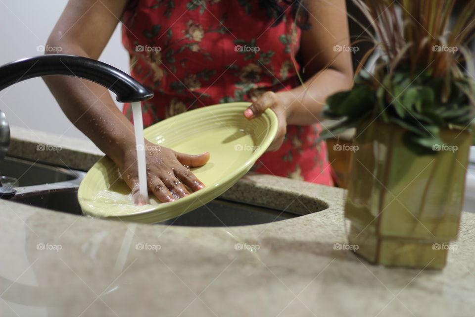 Woman washing plate in kitchen