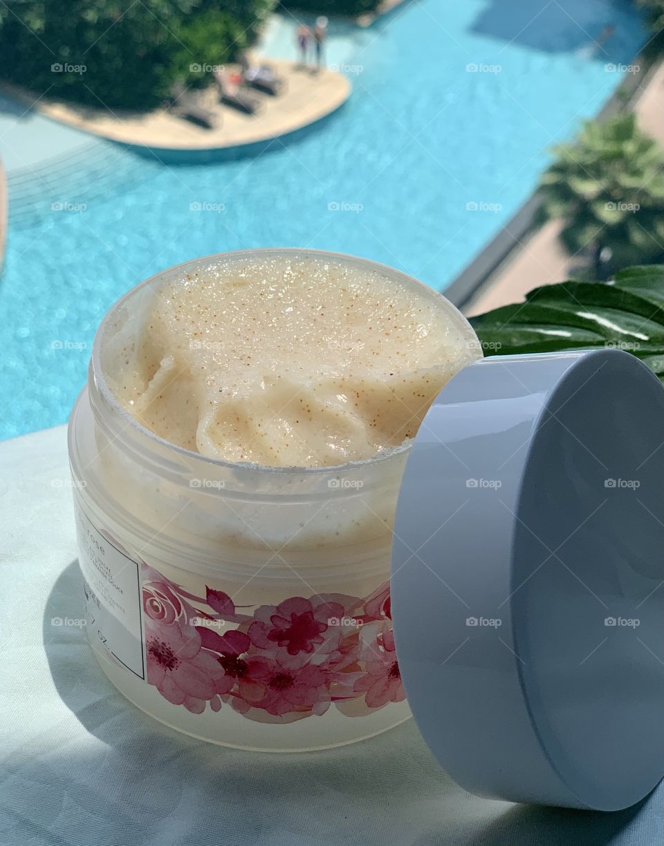 Body scrub in rose flavour set against swimming pool