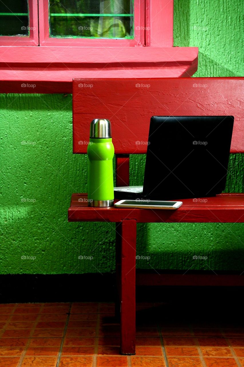 flask, tablet and laptop computer on an outdoor bench