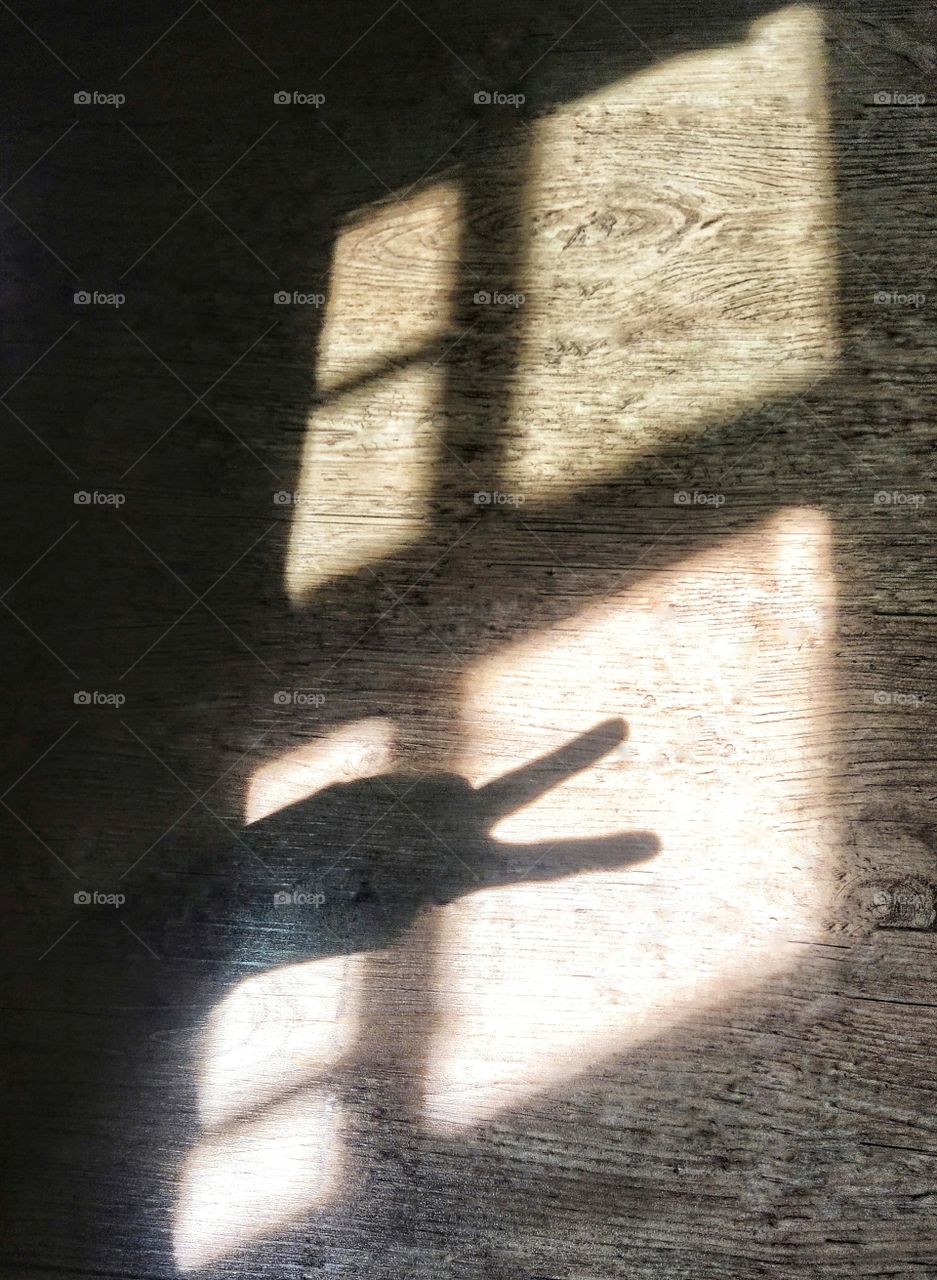 A peace sign✌ to the sun rays peeking through the window.