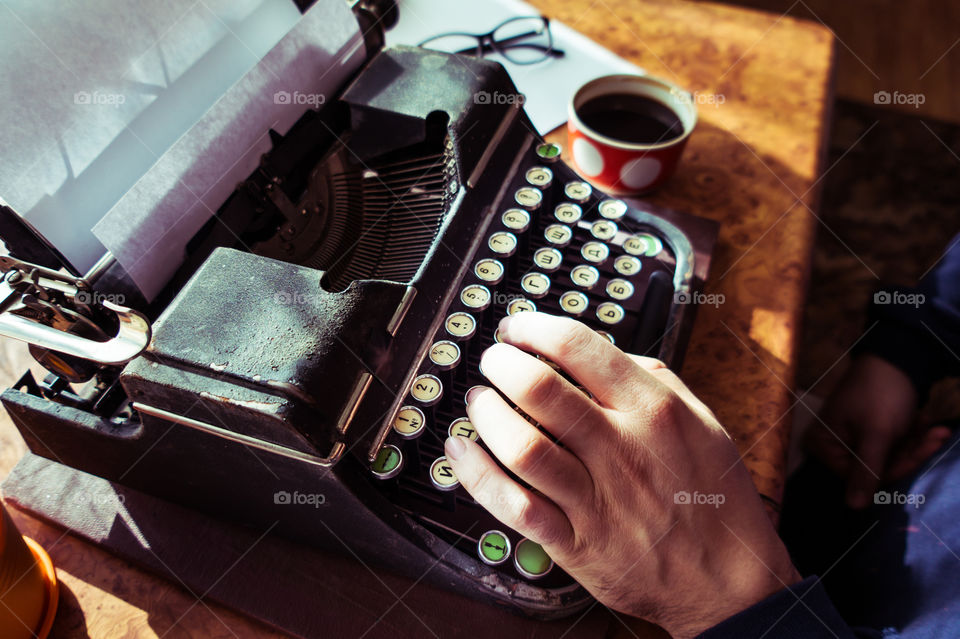 A young writer is writing a new book on an old typewriter.