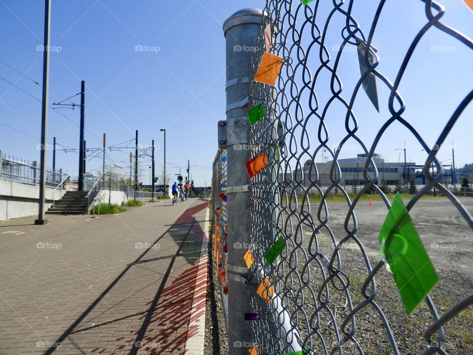 Color along a chain link fence. Love these colorful tags and how they really pop against the grey chain link. They are reflecting a light fun city life. 