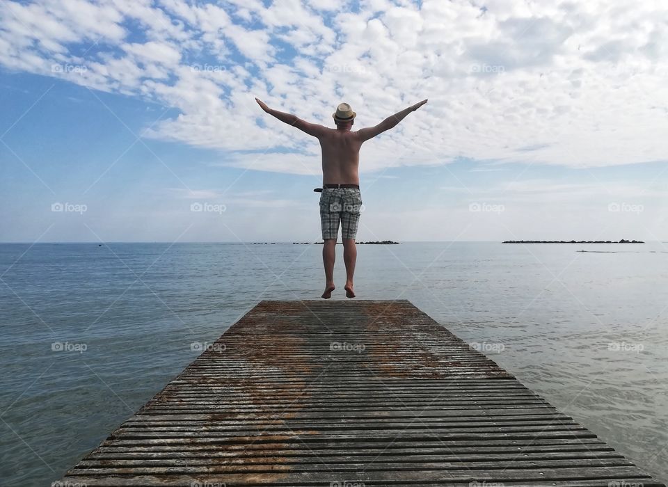 Man jumps on the jetty to the sea