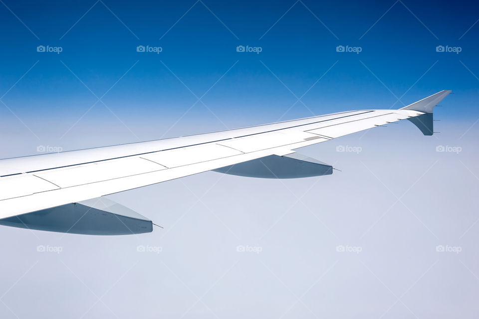 Airplane wing in milky sky.