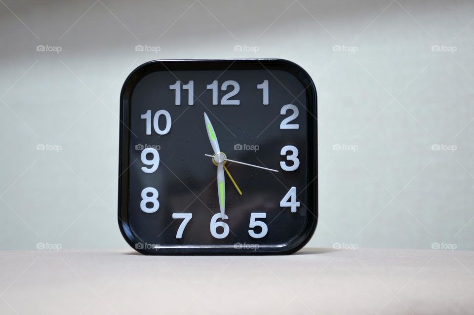 a black clock sits on the ottoman by the bed in the bedroom