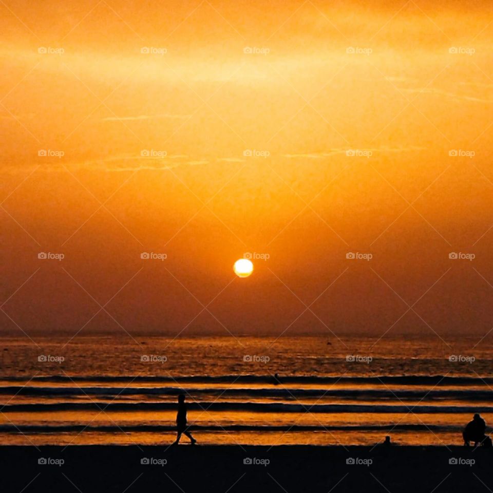 a young boy runing near to the sea with a sunset at essaouira city in Morocco