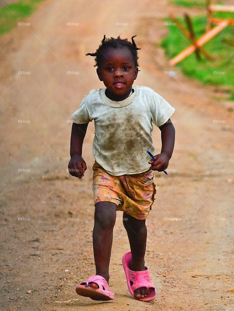 going to school. this little child was walking every day 5 km to school with his pensil and diferent flip flops