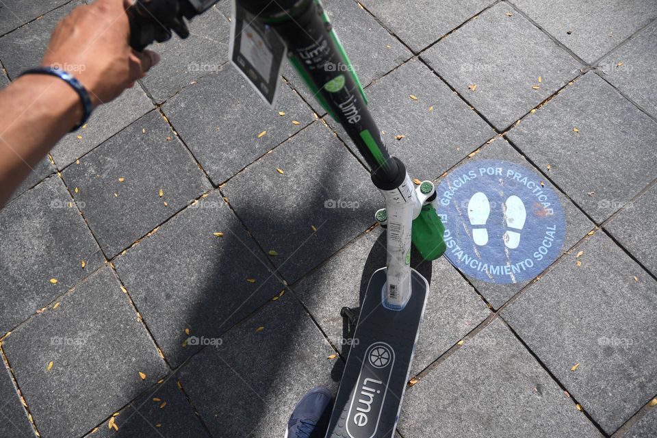 A man stands over a pay per hour scooter in preparation to take a ride and sight see.
