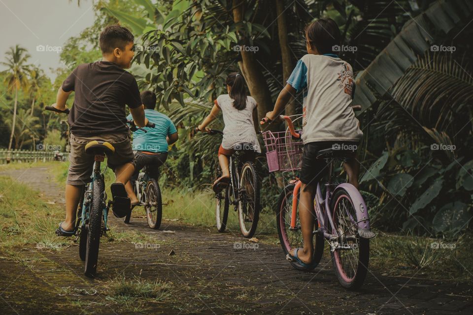 Four small children are cycling on the countryside