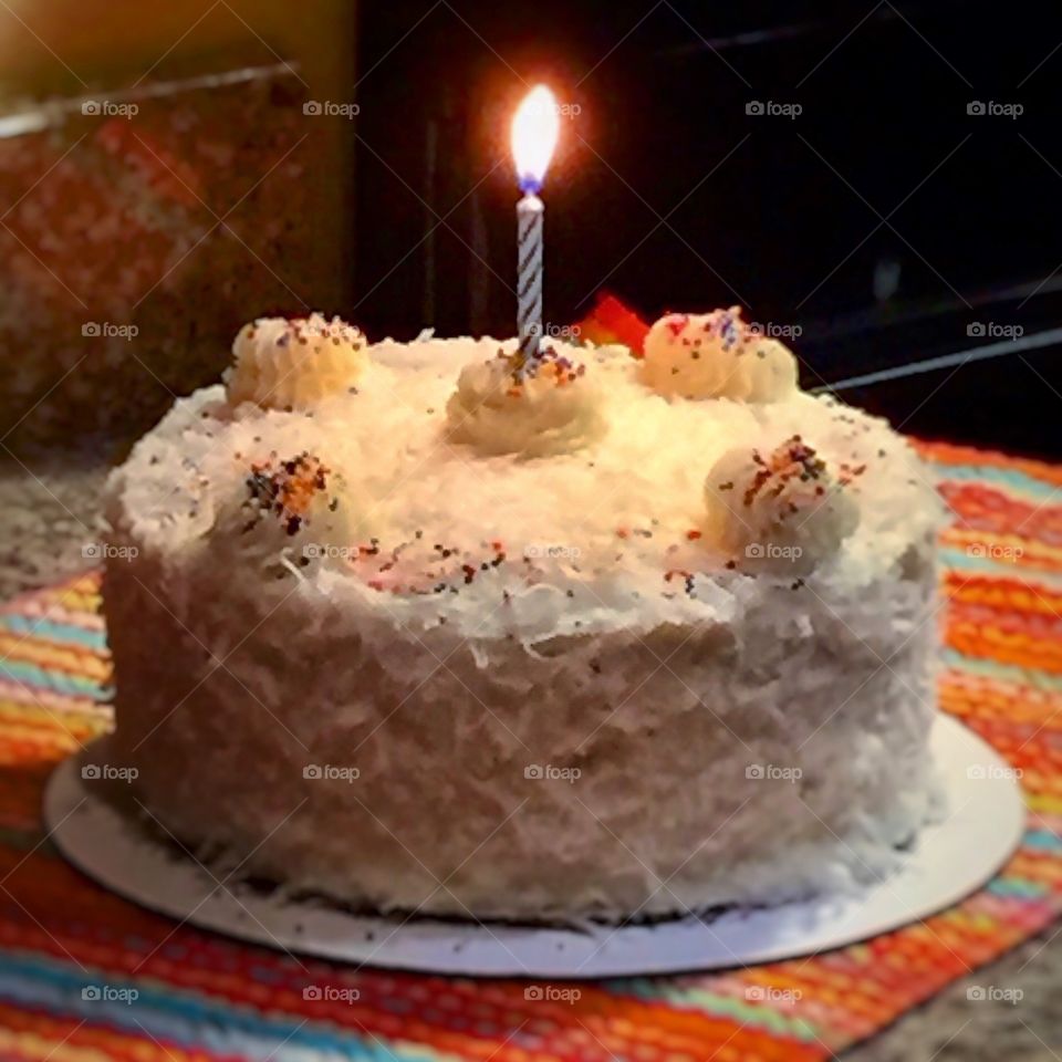 Coconut birthday cake with one candle lit