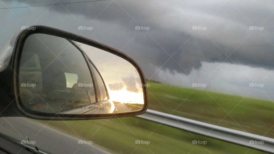 rear view mirror storm ahead, sun behind