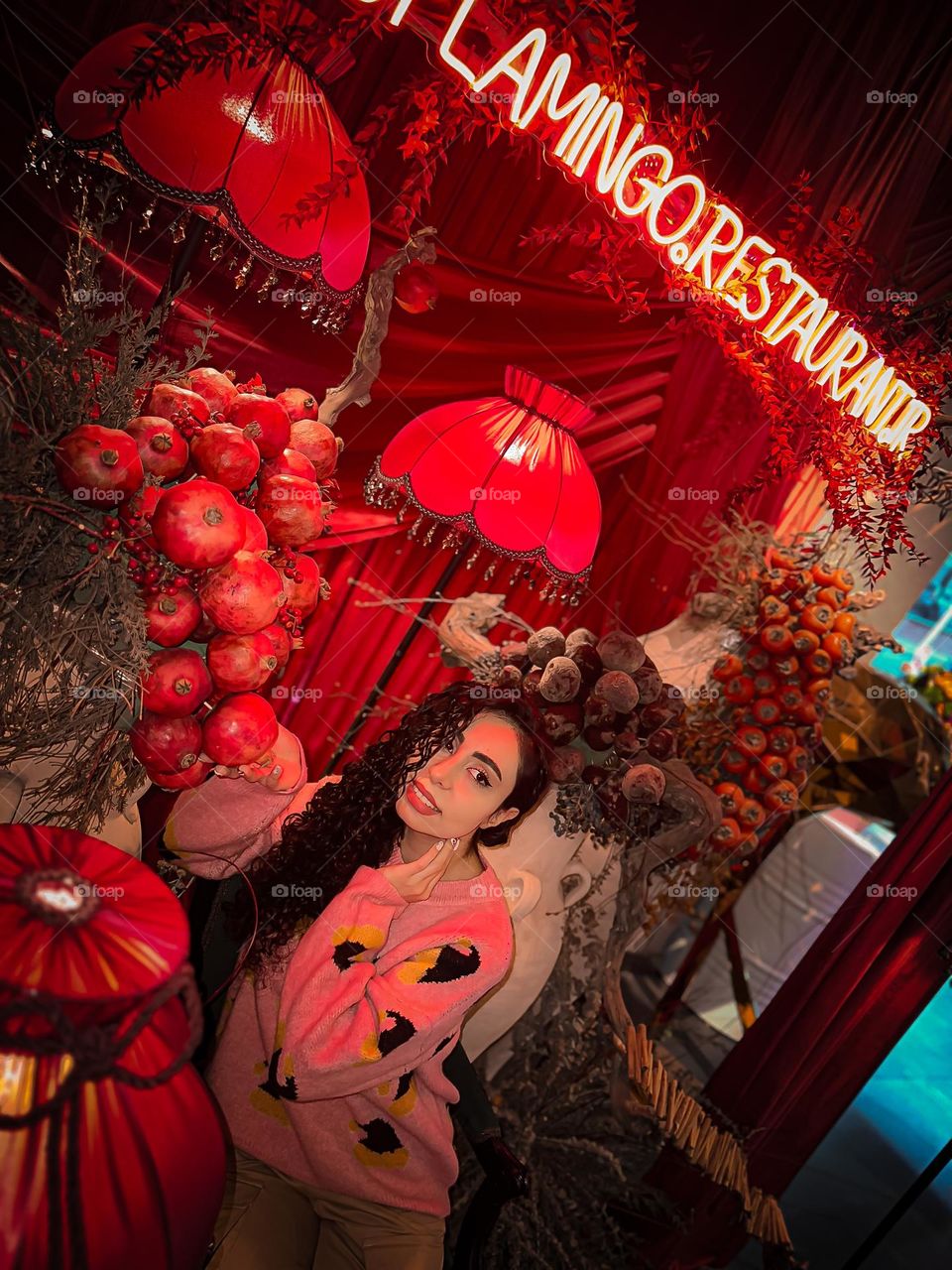 Girl with curly hair and clusters of pomegranates and persimmons in red decoration
