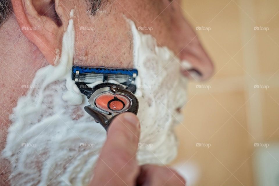 Man shaving his beard in the bathroom