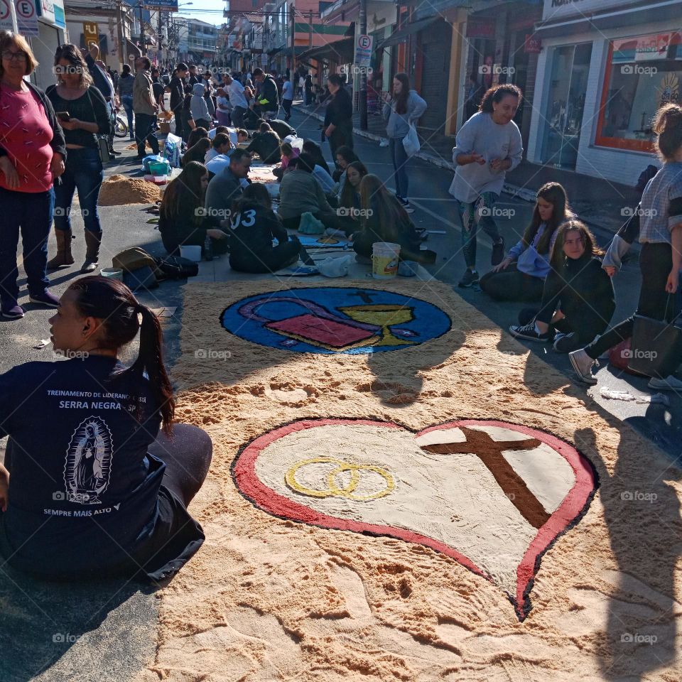 Small city main street crowded with devouts decorating it for Corpus Christi procession