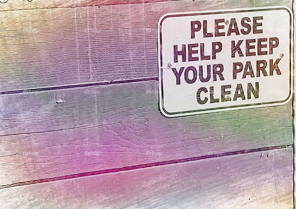 A Please Keep Your Park Clean Sign Mounted On Wood Planks. Photo Edited With A Rainbow Colors Around The Sign.