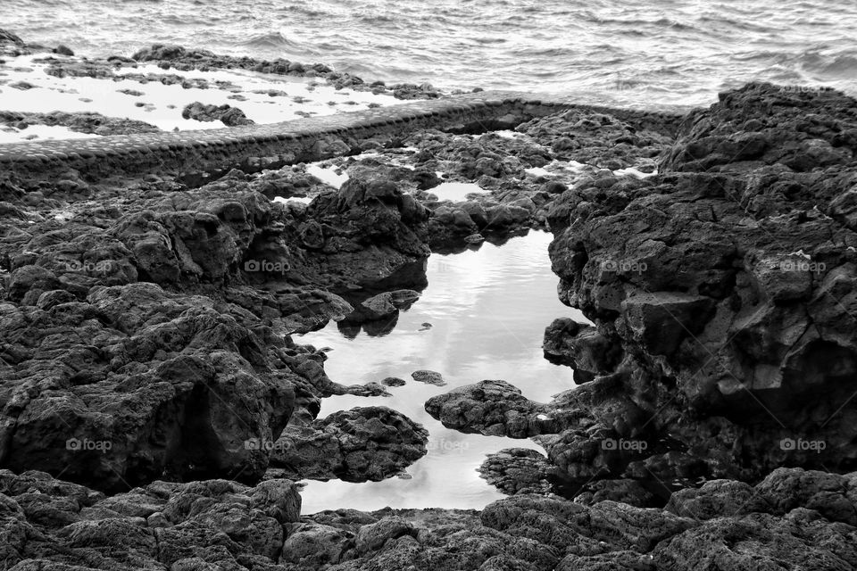 Black and white photo of a puddle between rocks in the atlantic ocean
