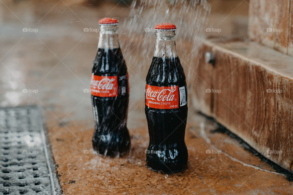 Two bottles of Coca-Cola under water shower